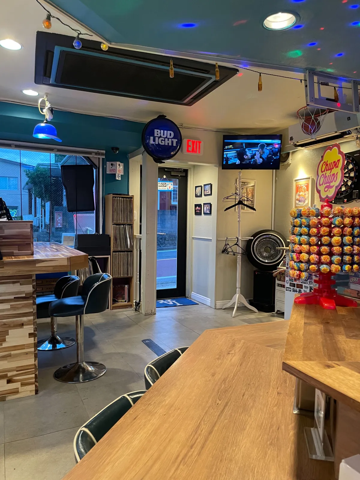レコードクレート、ダーツボード、Bud Lightのネオン、バスケットゴールが並ぶダイブバーの店内