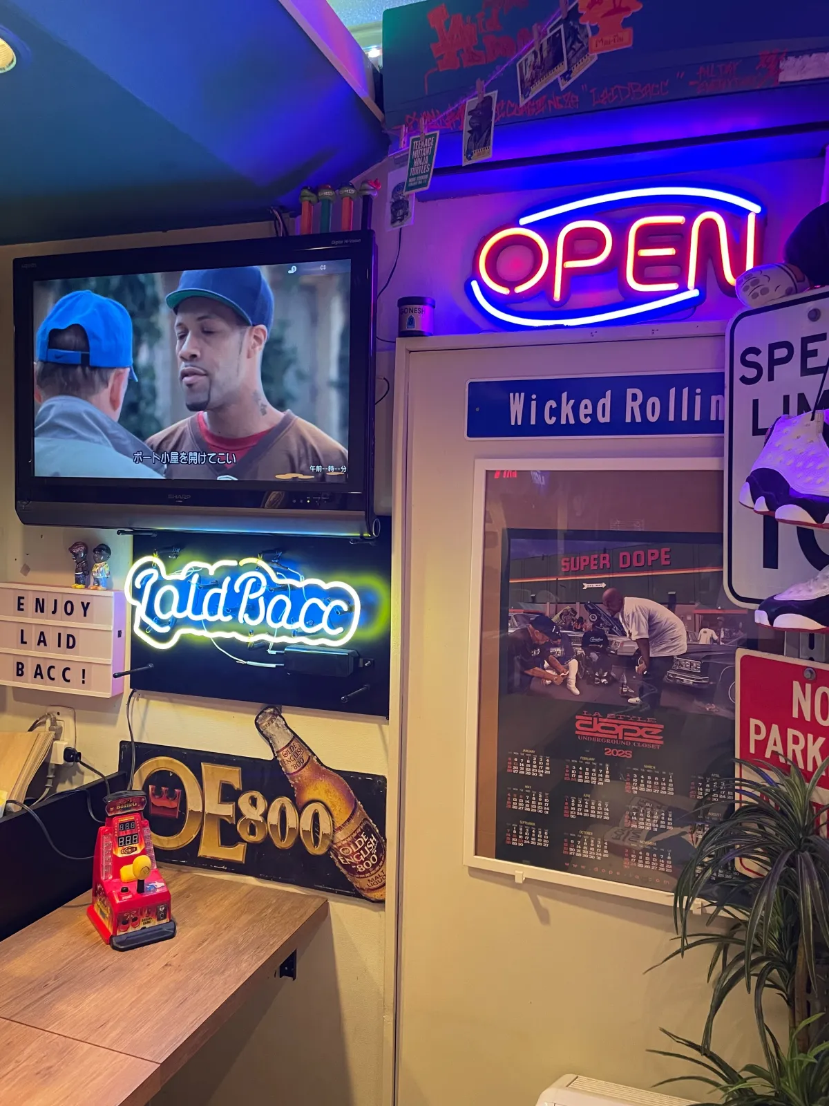 ネオンのOPENサインとLaid Baccネオン、ローライダーのカレンダーが並ぶ店内
