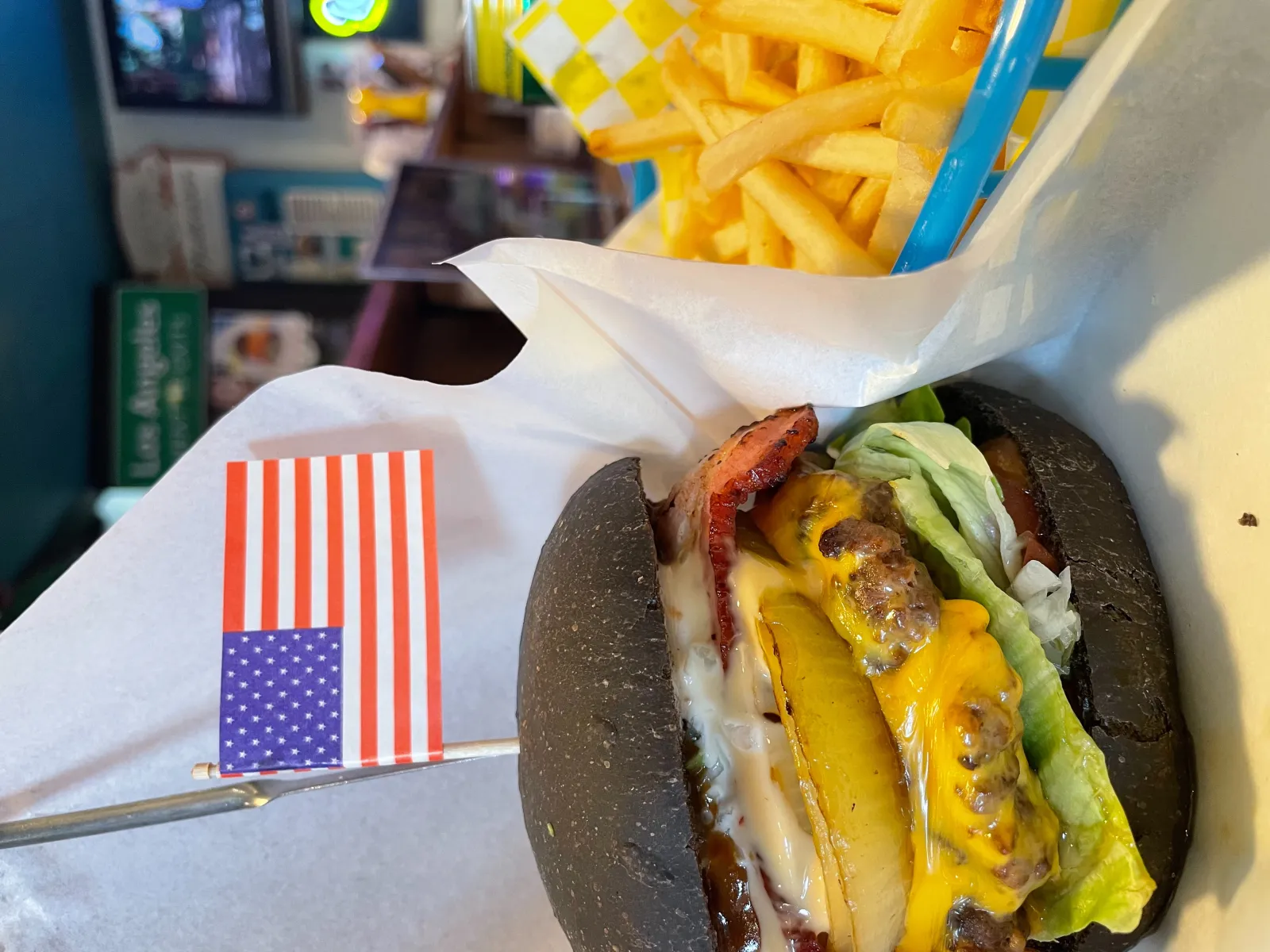 チャコールバンズの看板バーガー。ベーコンとグリルパイナップル、チェッカー柄カップのフライ添え