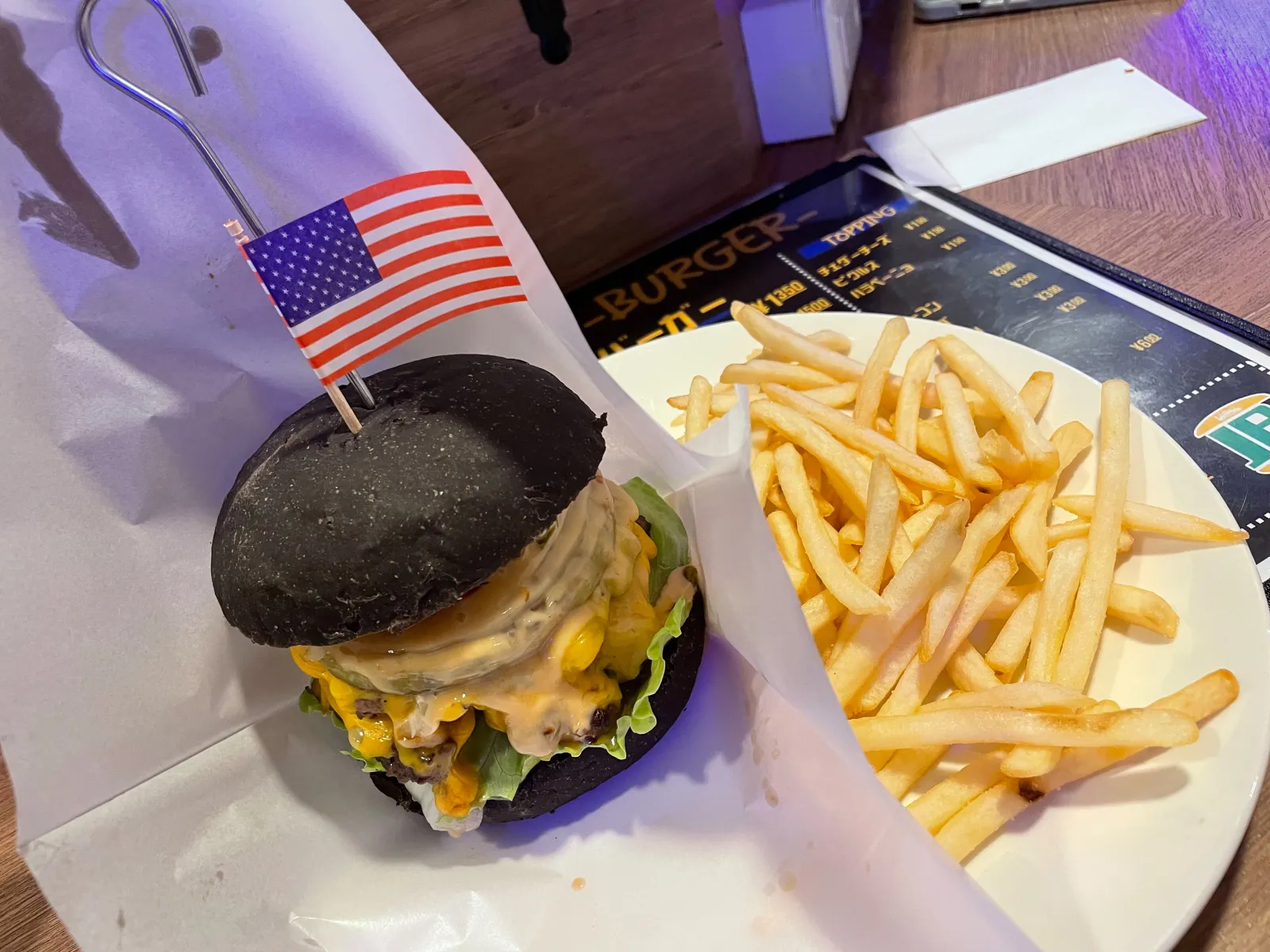 バーガーとフライがメニュー表の上に置かれた一皿。価格 ¥1350／¥1500 が見える